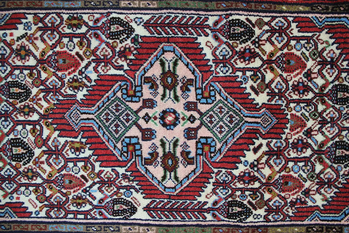 Close-up of a Hamadan rug: colorful geometric motifs in red, blue, and white
