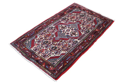 Hamadan rug shown at an angle, red field with decorative borders and ornaments