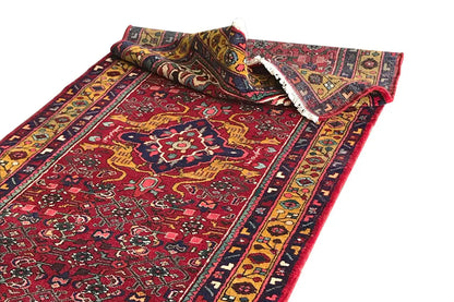 Red and multicolored Oriental runner rug with a border, turned-up edges, and decorative fringes