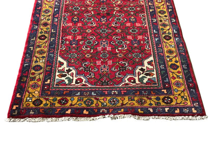 Red and multicolored oriental runner rug with borders, detailed patterns in blue and yellow, and fringes