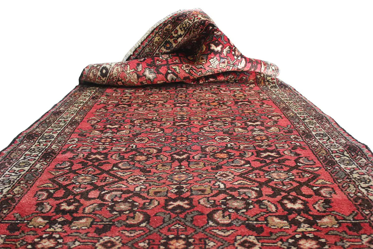 Oriental rug runner with a red central field, black pattern, and bordered edges