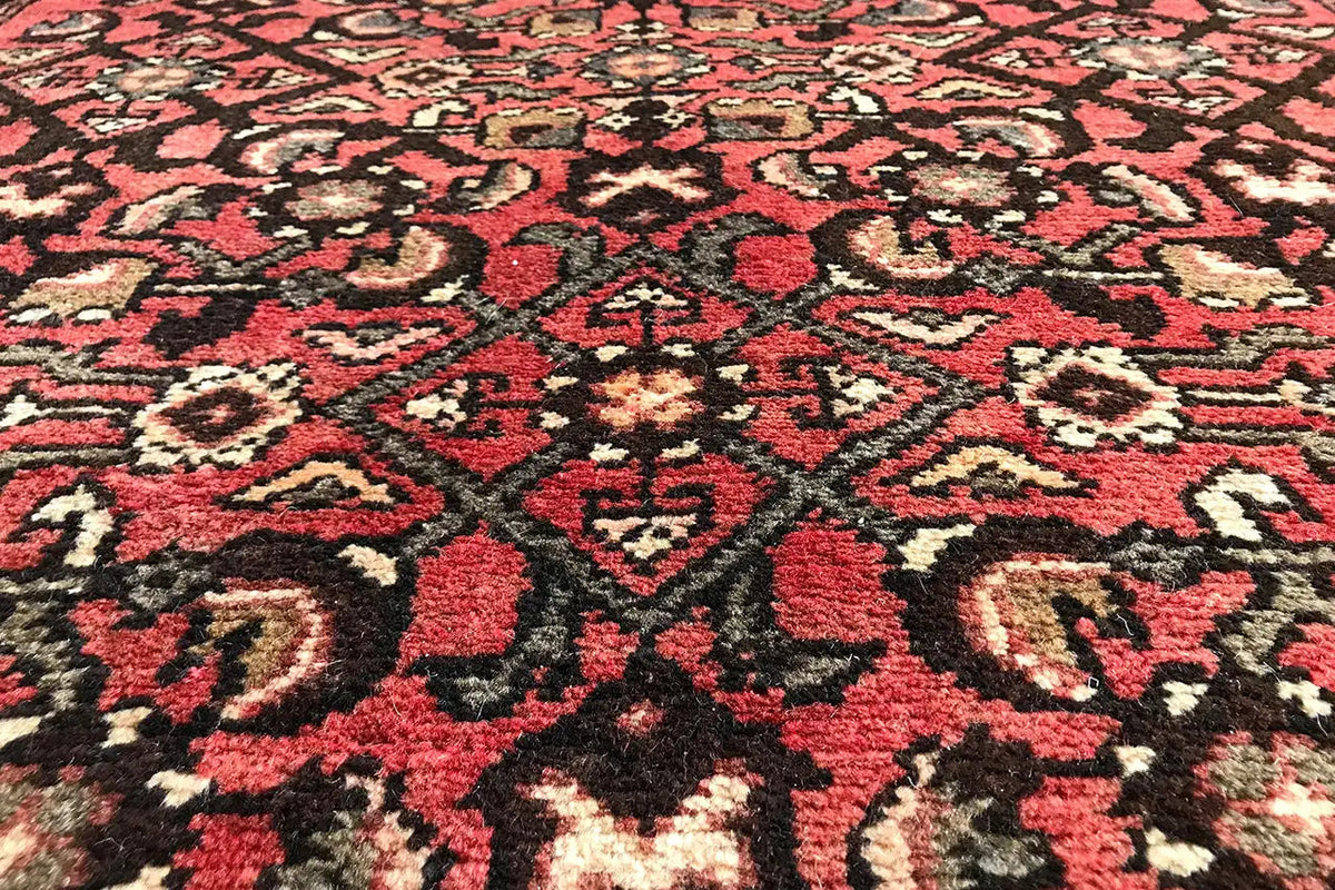 Close-up of an Oriental rug pattern: red background with black and beige ornaments