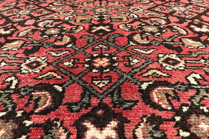 Close-up of an Oriental rug pattern: red background with black and beige ornaments