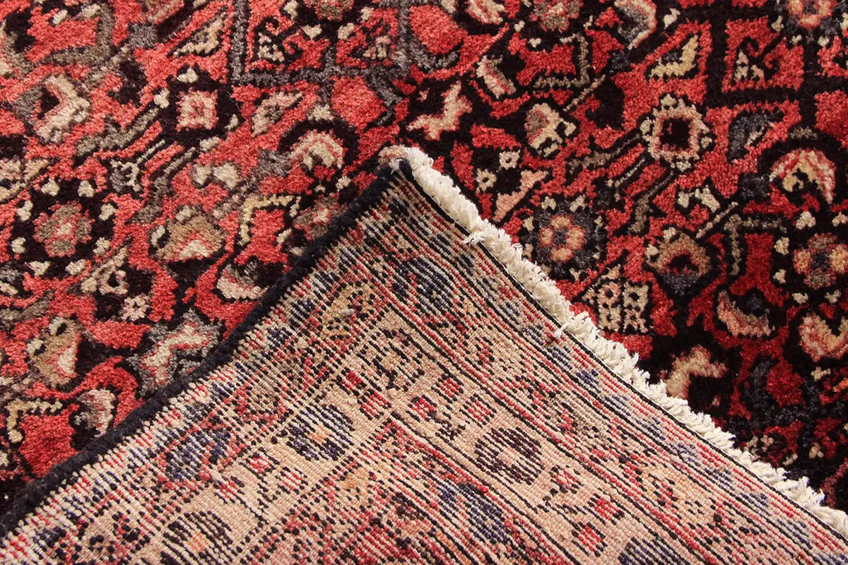 Carpet edge in detail: red background, hemmed border, and beige finish at the edge