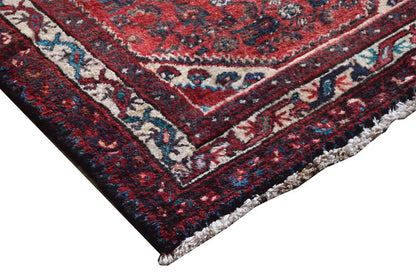 Oriental rug runner with a red ornamental pattern and multicolored bordered edge, with fringes