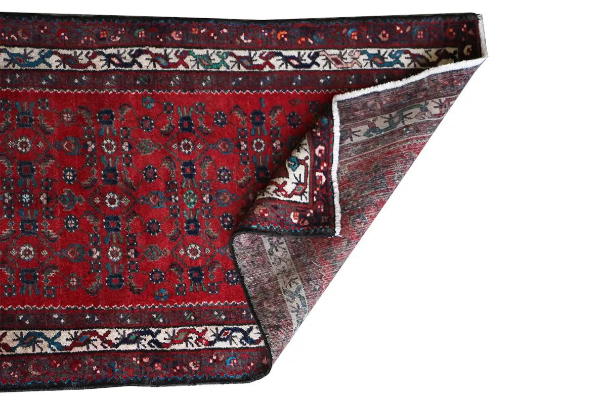 Oriental rug runner, red pattern with a blue-and-white border and visible edge finishing point