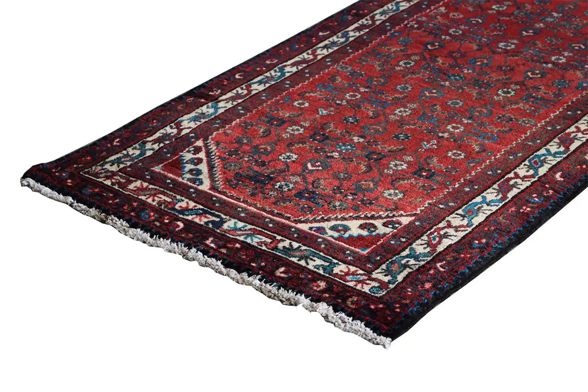 Oriental rug runner with a red background, blue-and-white central band, and fringes at the corners