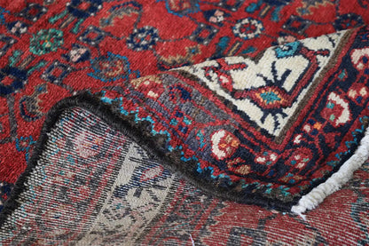 Detail of the oriental rug runner: red pattern with blue-green ornaments and a light pile border