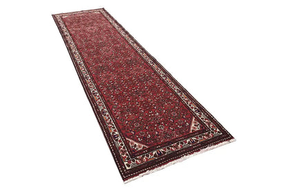 Red runner with a classic ornamental pattern, wide decorative borders, and finished edges