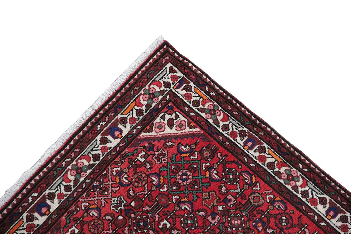 Triangular close-up of a red table runner with a patterned border and a clearly defined fabric edge
