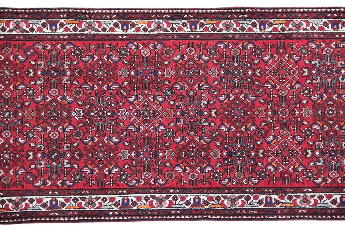 Red runner: uniform ornamental pattern with a decorative hem edge and trim stripes