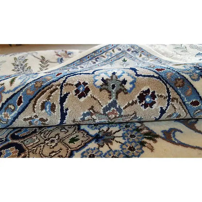 Carpet detail: floral ornament in cream and blue with a visible fabric fold