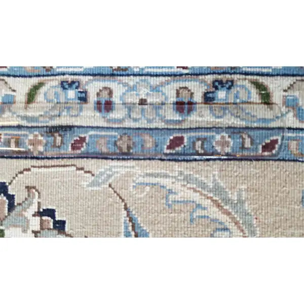 Close-up of carpet pattern: cream, light blue, dark ornaments and border