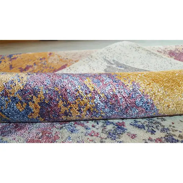 Designer rug edge with pile texture; beige base, blue-purple pattern
