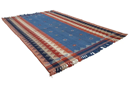 Rectangular rug with a blue central field, red-and-white stripes, dark blue borders, and fringes