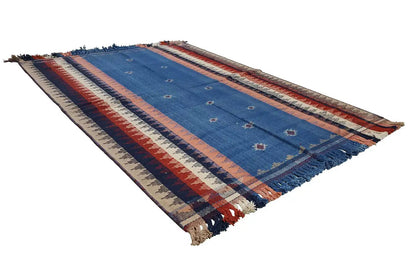 Striped rug in blue, red, and beige, laid diagonally with fringes