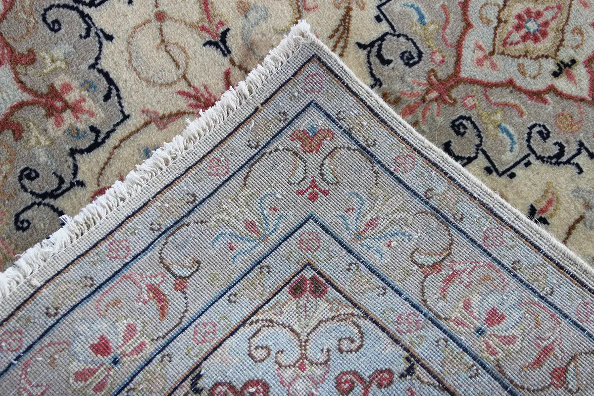 Keshan rug corner detail with fringes, beige pattern and blue-red ornamental design