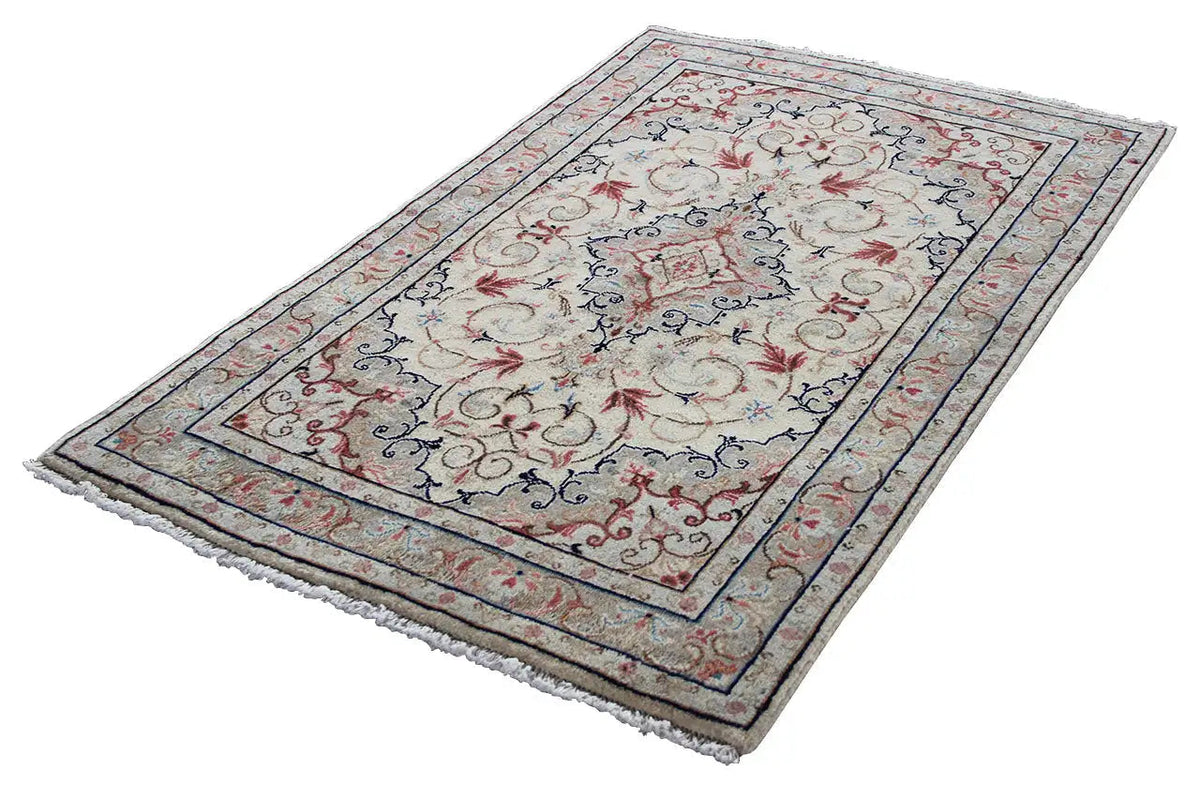 Beige Oriental rug lying flat, with a wide blue border featuring red patterns