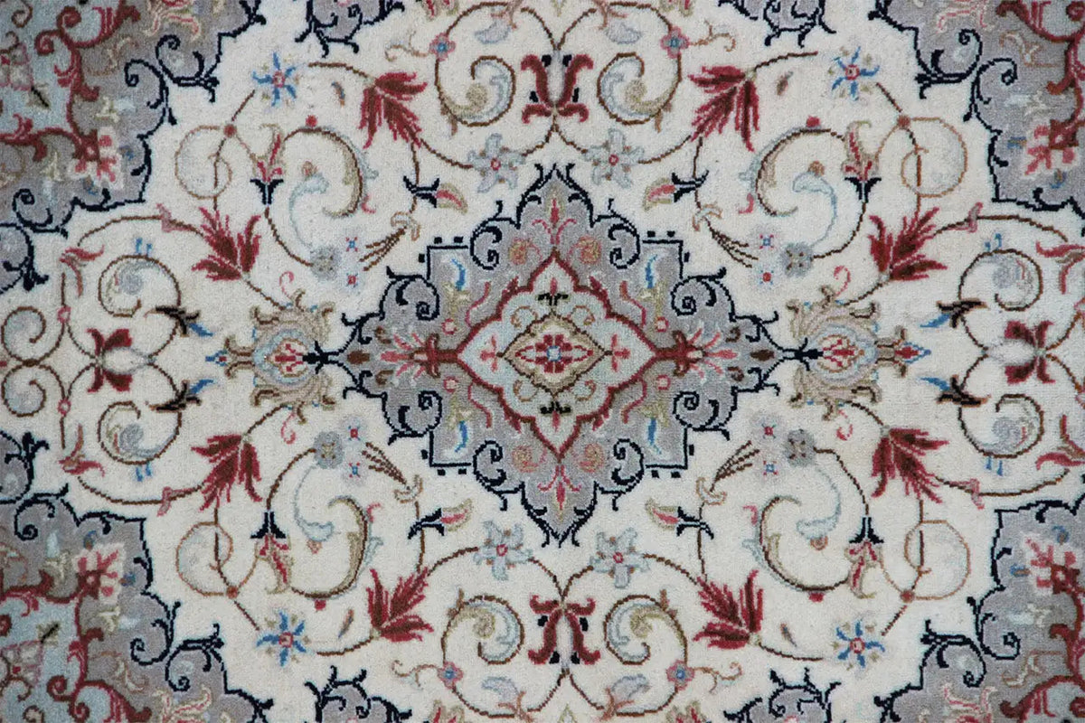 Close-up: beige carpet with a blue ornamental band and red flowers in the central motif