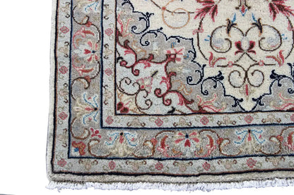 Close-up detail of a beige Oriental rug with a blue border, red decorations, and fringe