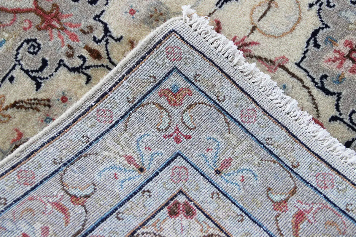 Fringed corner: beige oriental rug with a blue border and red ornamental motifs