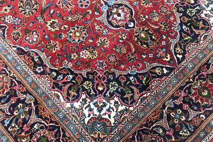 Close-up of an Oriental rug with a dense floral pattern in red and a dark background