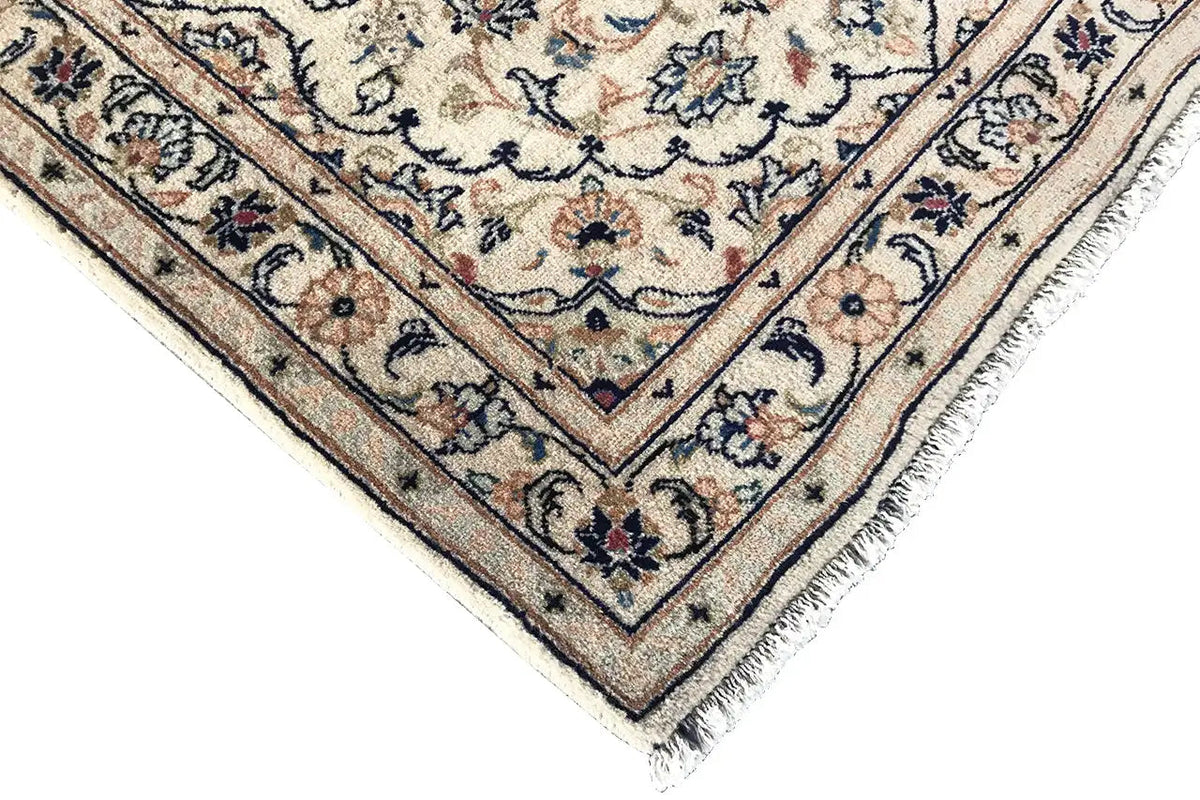 Corner view: light border with blue and beige motifs, with fringe along the hem below