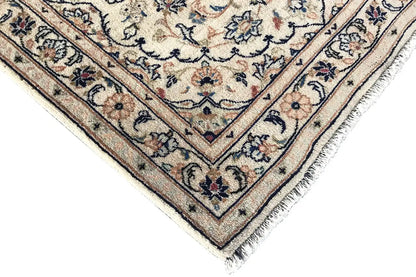 Corner view: light border with blue and beige motifs, with fringe along the hem below