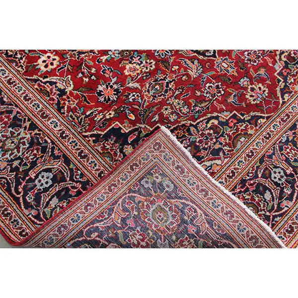 Close-up of an Oriental rug: red-and-blue ornament, light border line, and knot pattern