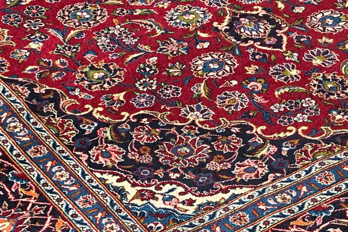 Keshan carpet with a red background and richly decorated floral motifs in blue and green