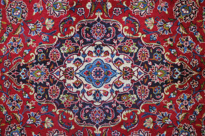 Keshan rug with a red background, a blue-and-white medallion, and colorful garland ornaments