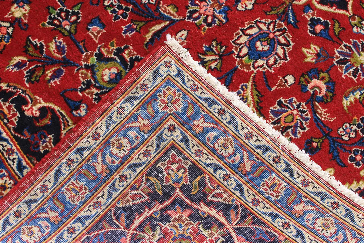 Red Oriental rug with a blue medallion and floral ornaments, detailed close-up