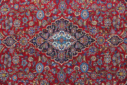 Red Kashan rug with a floral pattern and central medallion in blue, beige, and green