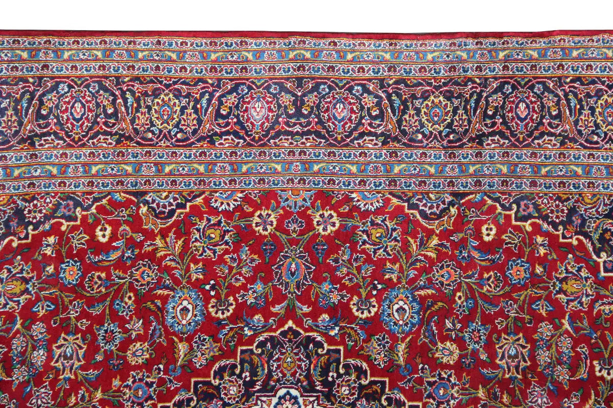Red Keshan rug with a border of vines and medallions along the upper edge