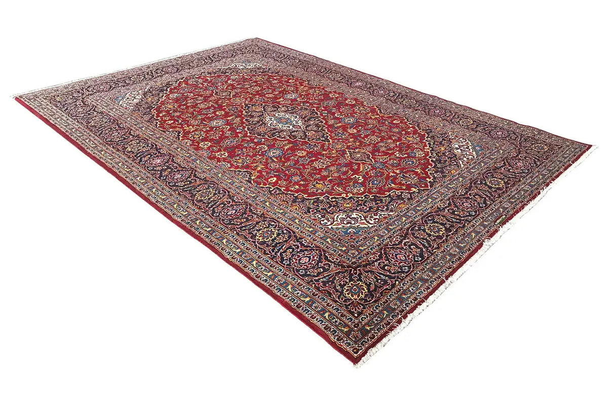 Red Keshan rug shown at an angle, with a central medallion and decorative border
