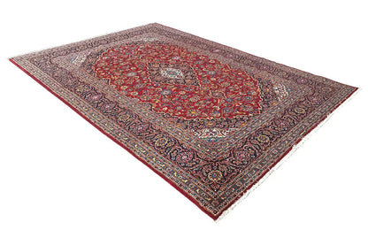 Red Keshan rug shown at an angle, with a central medallion and decorative border