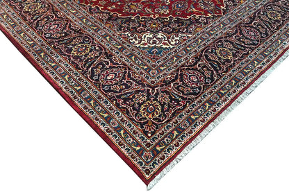 Keshan rug in red: corner area with a dark vine pattern, decorative border and lines