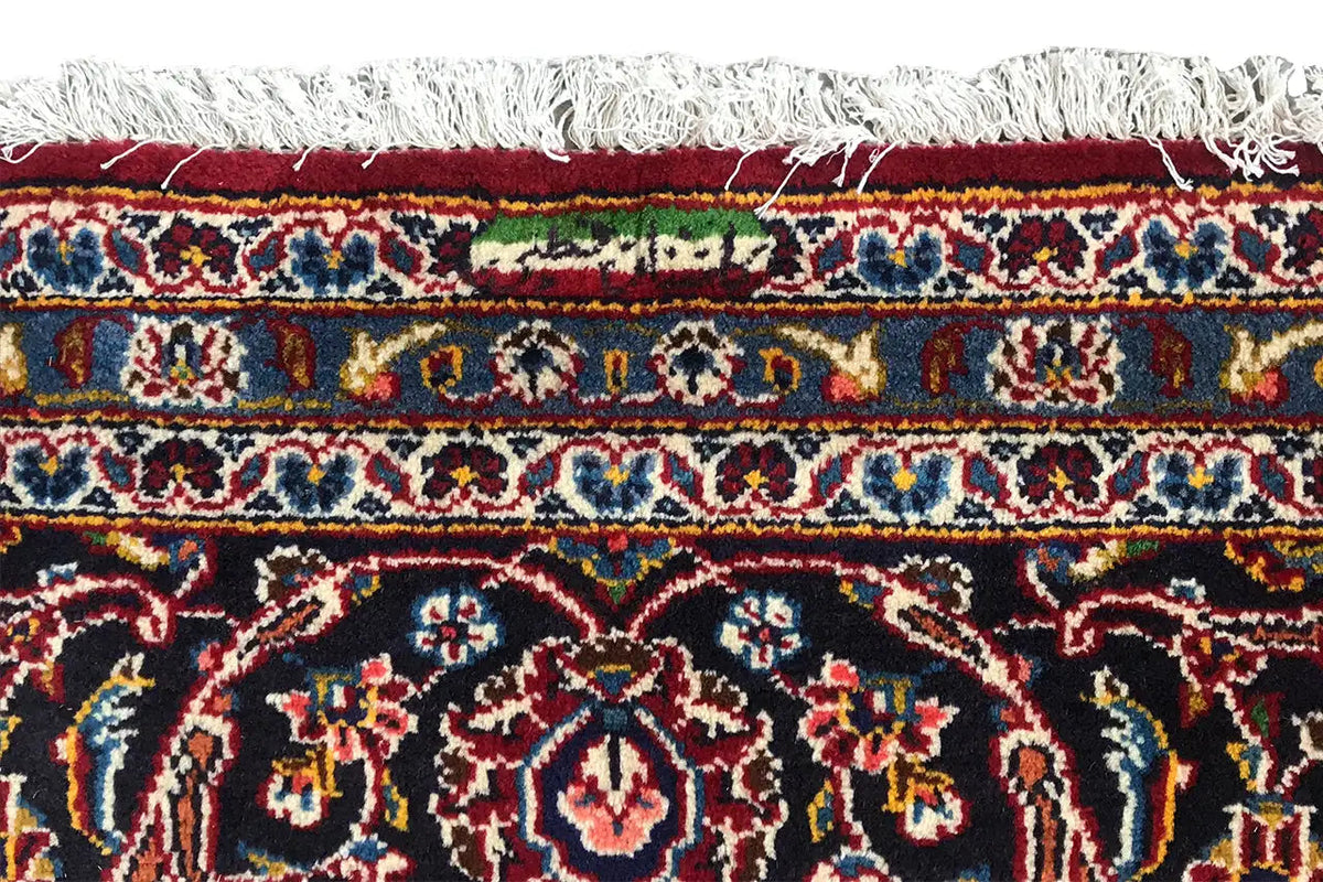 Red Keshan rug with fringed edging and a decorative border along the edge