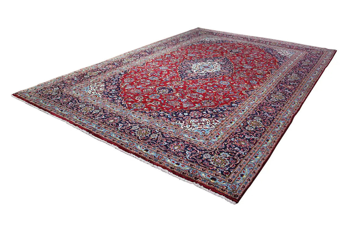 Rectangular Keshan rug in red with a blue ornamental border and central medallion.