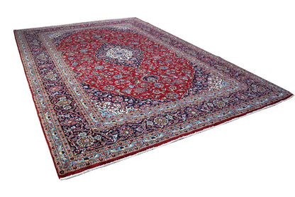 Diagonally spread Keshan rug in red, with a medallion and detailed border.