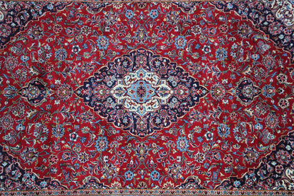 Rust-red Keshan rug with a dense paisley and floral pattern in the center.