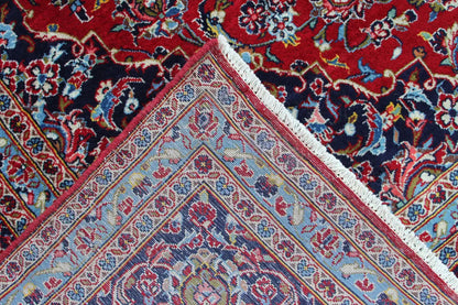 Detail at the edge: red Keshan rug with a multicolored border and white trim.