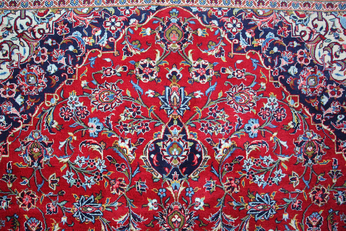 Close-up: Keshan rug in vivid red with a blue, floral all-over pattern.