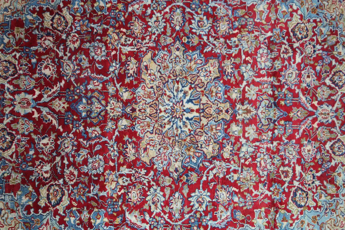 Detailed view: Red-and-blue ornamental pattern on an oriental rug with fine lines.