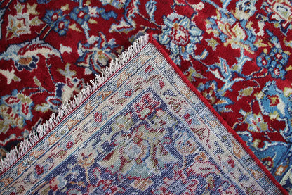 Close-up: Woven ornamental pattern in red, blue and beige along the edge.