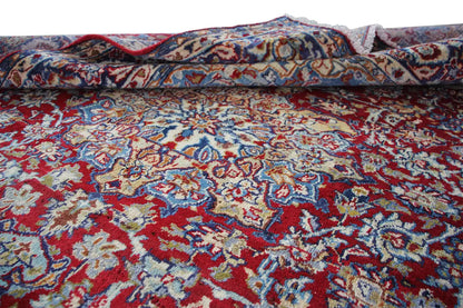 Rolled oriental rug with an ornamental pattern in red and blue, visible edge.