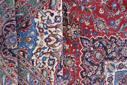 Keshan rug detail with a red background, blue pattern, and floral ornaments.