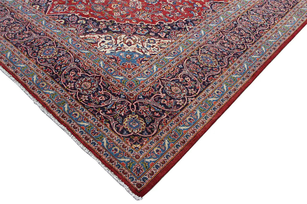 Keshan rug corner detail with a red background and patterned border ornament.