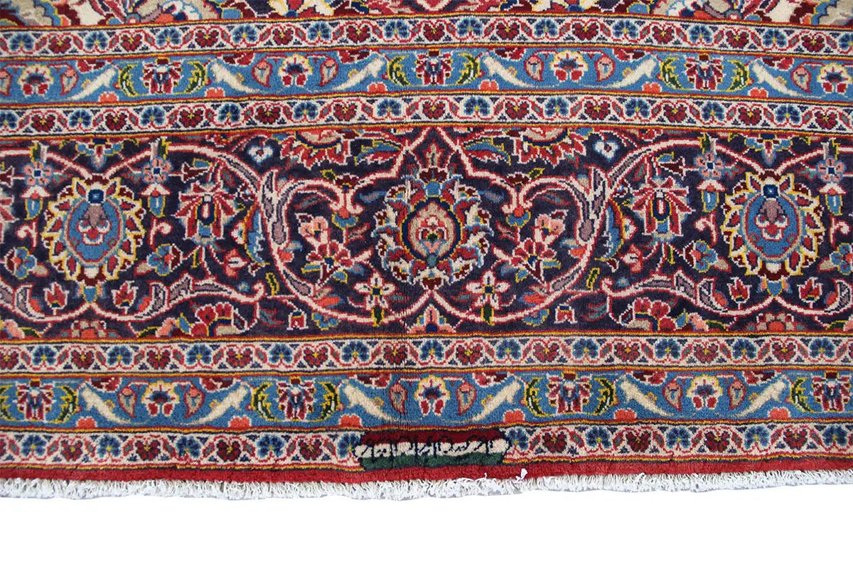 Keshan rug border with fringe along the edge, patterned in dark blue and red.