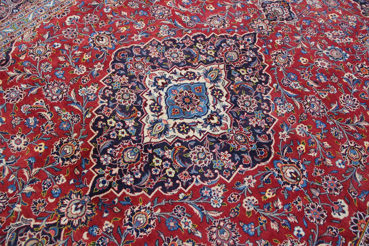 Keshan rug with a red background, dark vine patterns, and central medallions.